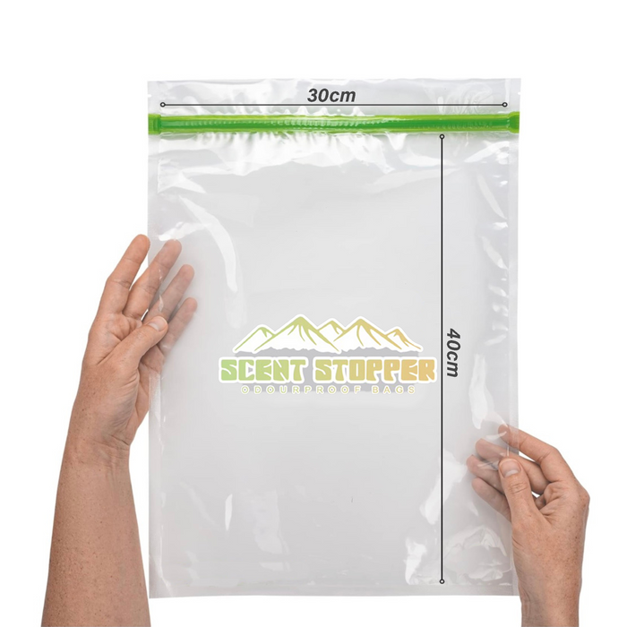 Two hands hold a transparent Ultralight Hiker Scent Stopper Odourproof Food Bag with a green seal. The hermetic closure keeps contents fresh and protected, and the 30 cm x 40 cm size is clearly marked on the front.